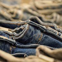 A detailed close-up view of neatly folded denim jeans stacked together, showing texture and stitching.