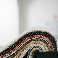 A detailed view of multicolored fabric samples displayed in a roll, showcasing intricate knitted textures.